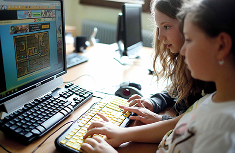 Zwei Mädchen spielen am Computer.